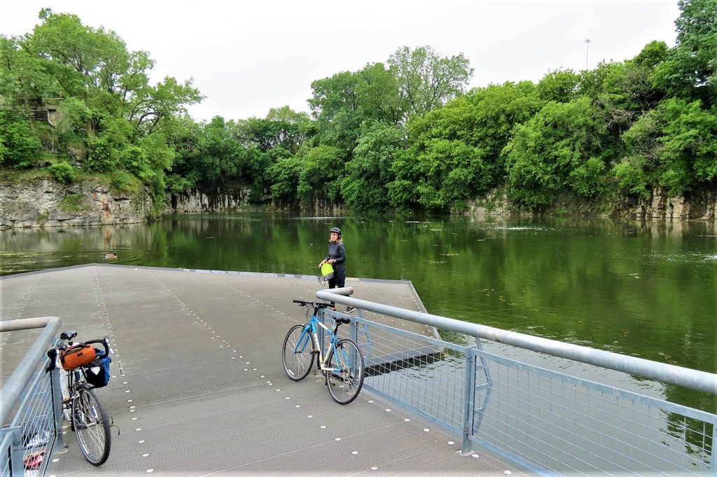 A CBA bie tour rider standing at the edge of a quarry pond