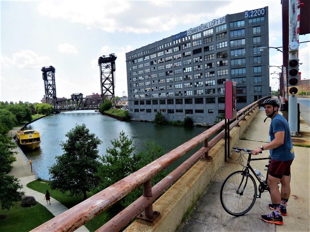 CBA bike tour rider with a vertical lift bridge and yellow water taxi in the background