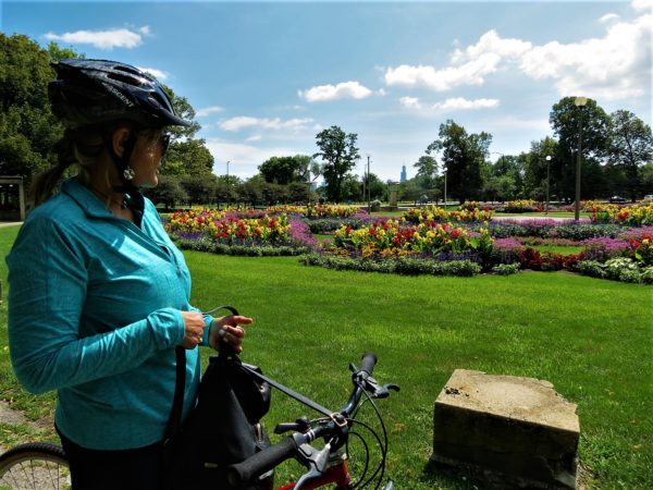 A CBA bike tour rider in the foregrund with a colorful flower garden in the back.