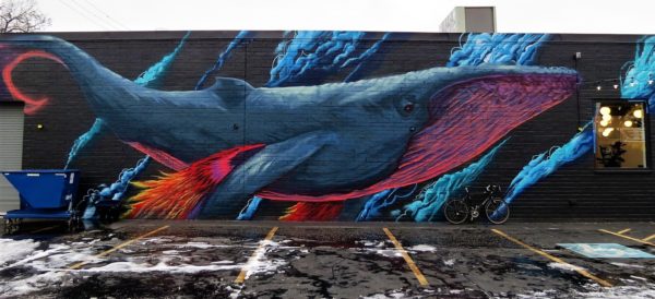 A tour bike leaning on a mural of a whale  on a black and bright colored highlights.