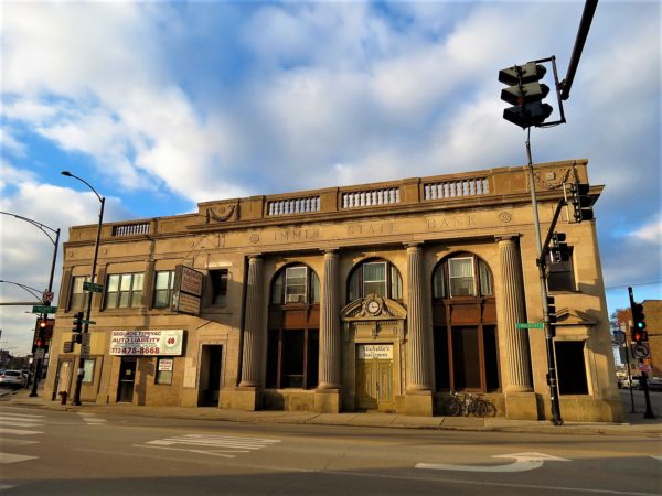A tour bike leaning on gray stone Classical Revival former bank building