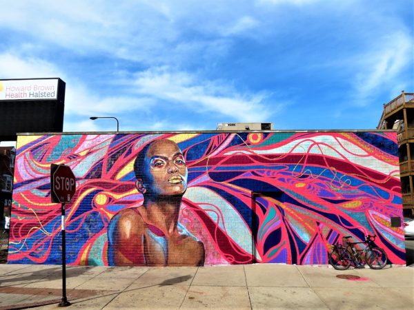 A tour bike leaning on a bright purple, pink, and blue mural with an bald African American figure.