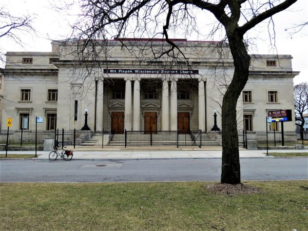 A tour bicycle standing in front of a white stone Classical Revival /Art Deco former synagogue