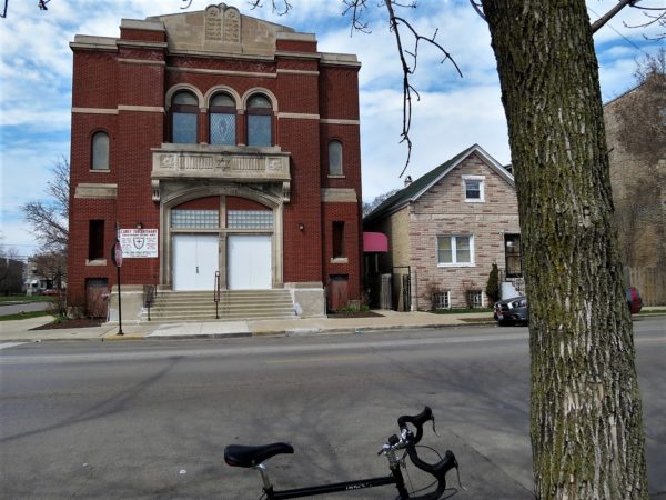 A tour bicycle with a former synagogue with red brick and stone details that include a Star of David and the Ten Commandments in Hebrew