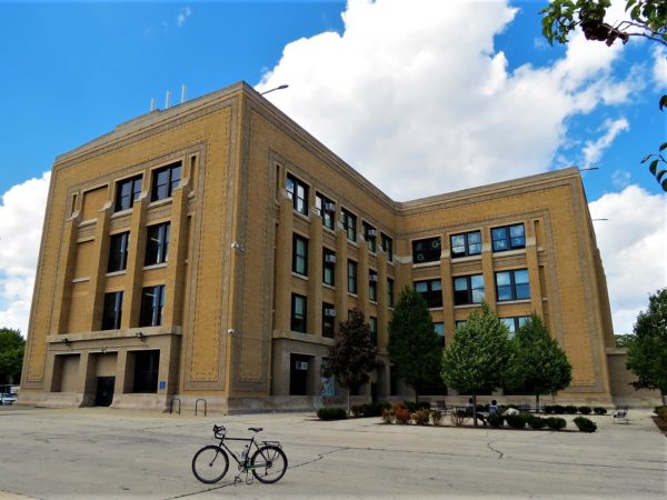 A tour bicycle standing in front of a tan brick patterned four story Prairie style building