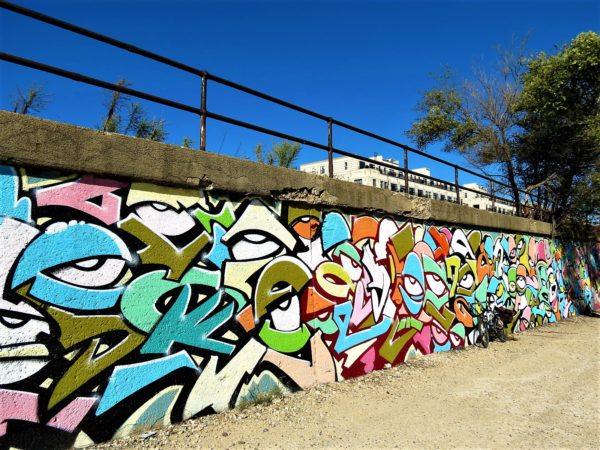 A tour bicycle leaning on a multicolored mural with eyes and hidden words 