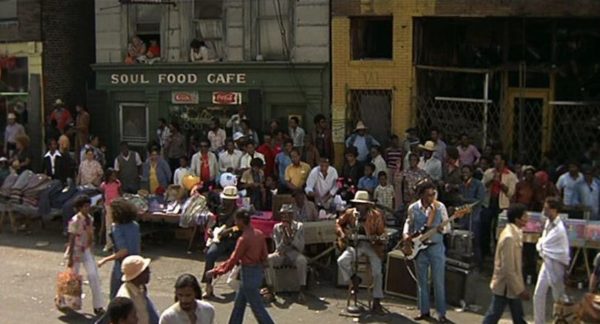 A Blues Brothers movie still of John Lee Hooker and band playing on crowded Maxwell Street