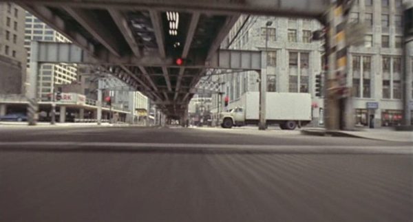 A first person POV blues Brothers movie still under an elevated train with a big white delivery truck edging in at the right.