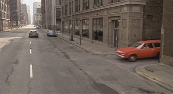 A Blues Brothers movie still of a red pinto pulling out of an alley
