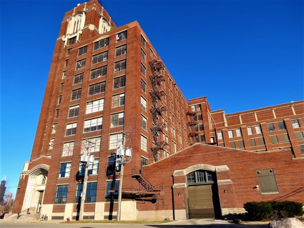 A tour bike leaning on a large red brick warehouse and tower