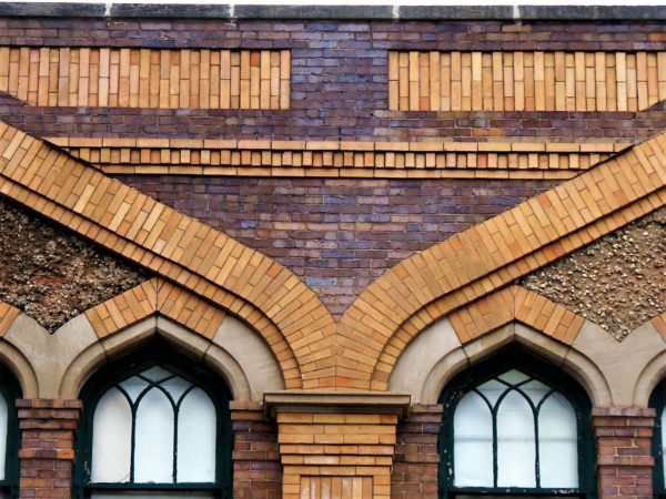 A close up detail of tan and brwon brick design work around arabesque windows