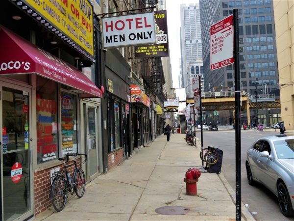 A tour bike leaning on a storefront with a Hotel Men Only sign above