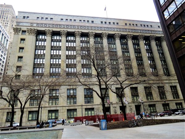 A tour bike leaning under a leafless tree with the Classical Revival Cook County Building in the background