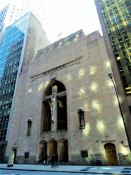 A tour bike in front of an Art Deco church facade with three story entry arch filled with a two story Art Deco crucifix