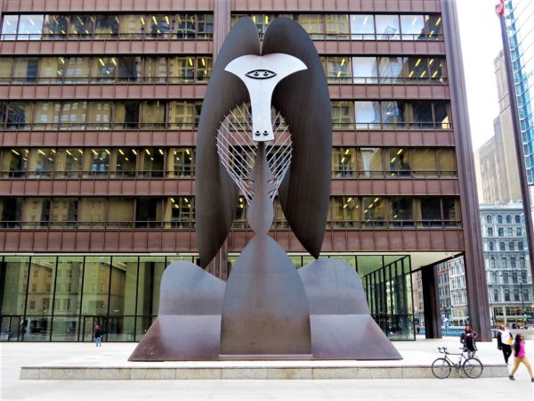 A tour bike standing next to a bronze statue a baboon like figure.