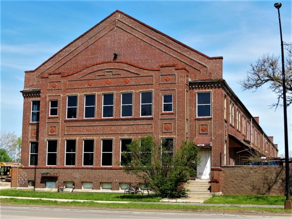 A tour bike leaning on the front of a Craftsman style red brick warehouse/factory