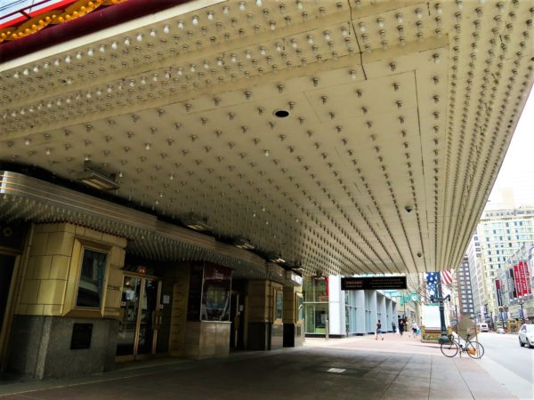 A tour bike standing in the background with the the white underside of a light bulb studded metal marquee looming above