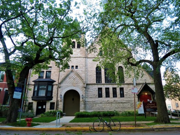 A tour bike standing in front of a white limestone Romanesque church.
