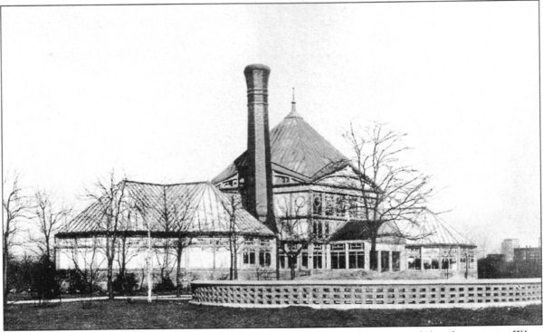 A historical black and white 1880s greenhouse with a smokestack.