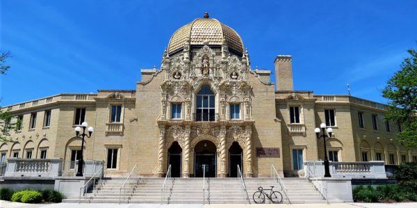 A tour bike standing on the steps of a gold dome building with Spanish Baroque Revival terra cotta facade.