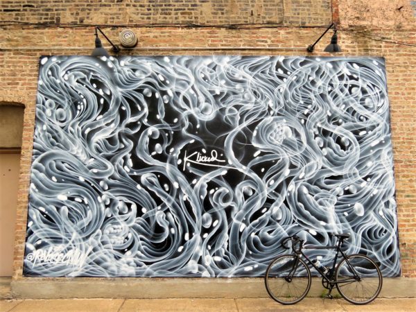 a tour bike leaning in front of a black and white organic Expressionist mural
