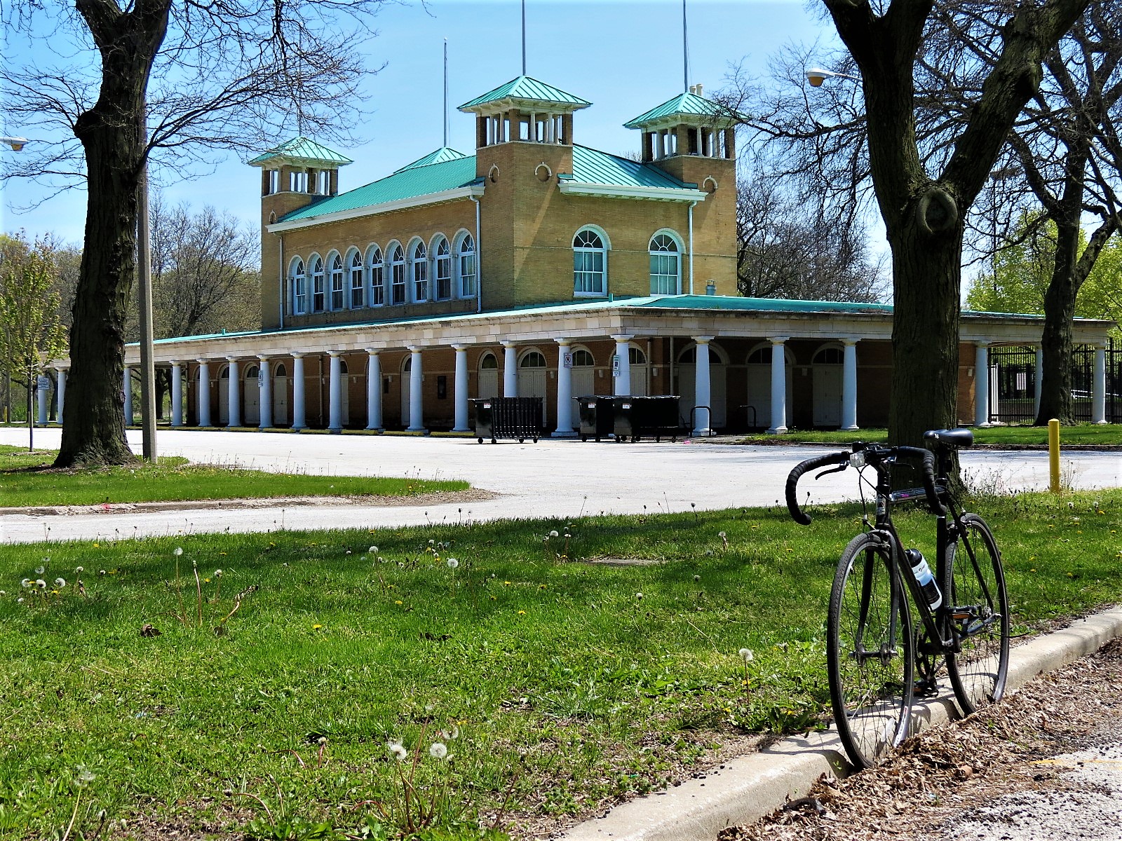 A tour bike standing in the foreground with a two story 1890s two story building with corner towers on the center mass and a collonade veranda around the first.