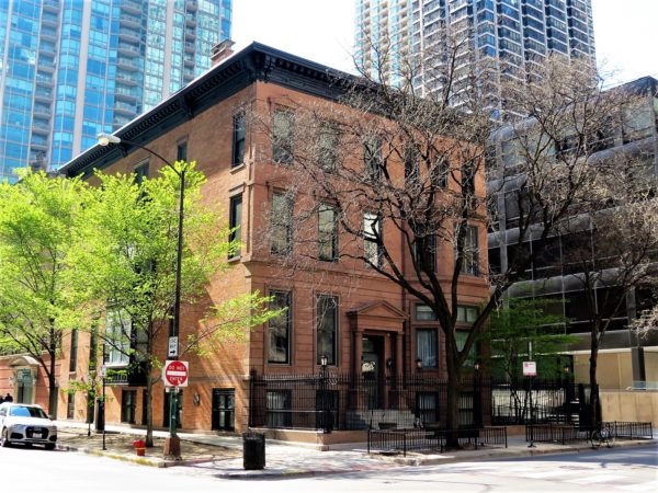 A tour bike standing in front of a red brick black cornice Italianate 3 story building,