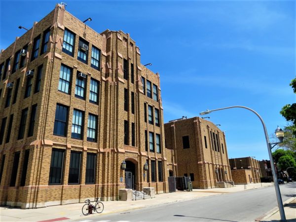 A tour bike standing in front of a light tan brick Gothic Revival four story school,