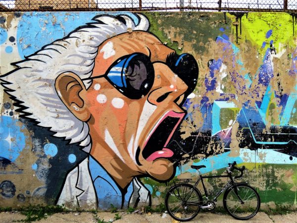 A tour bike leaning on a wall with a cartoon style screaming head  of the character Doc Brown of Back to the Future