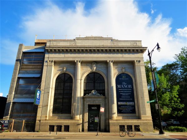 A tour bike standing at the curb in front of a limestone Classical Revival three story former bank building.