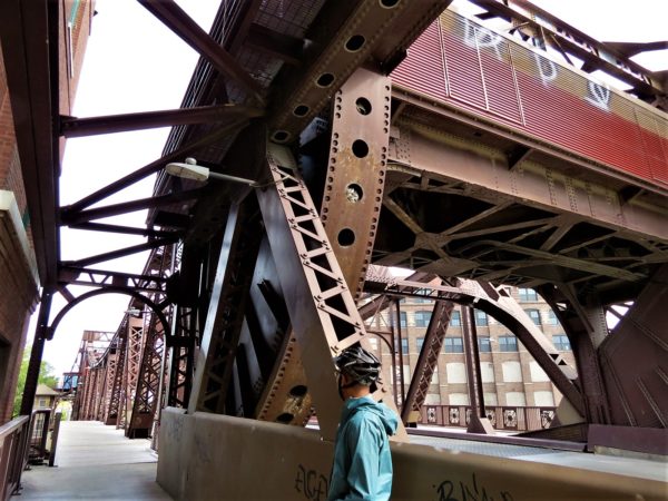 A CBA bike tour rider looking at a maroon painted steel roll type movable bridge.