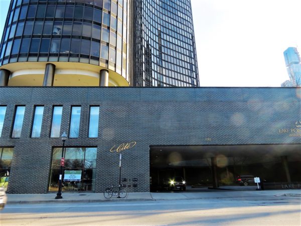 A tour bike standing in front of the driveway exit at the base of a glass tower.