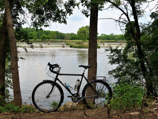 A tour bike standing between trees with man made water cascades in the background.