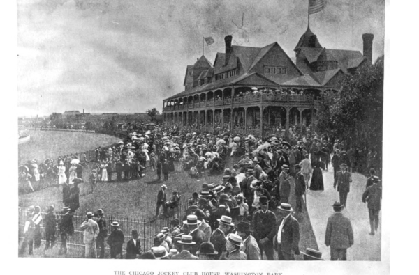 A historical black and white of a crowd in turn of the century clothing on a grassy slope in front of a three story Queen Anne structure