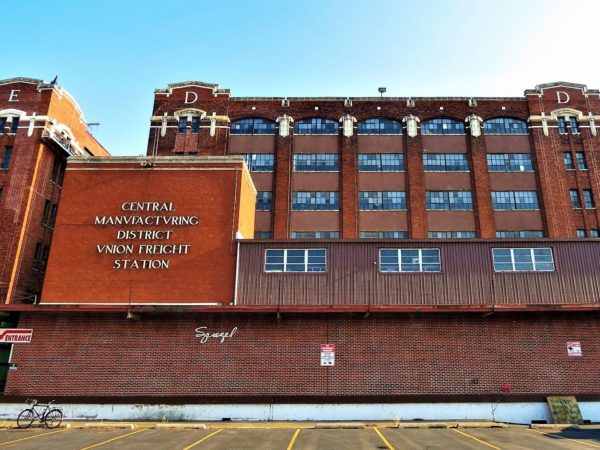 A tour bike standing in front of a red brick and terra cotta accented early 20th Century factory.