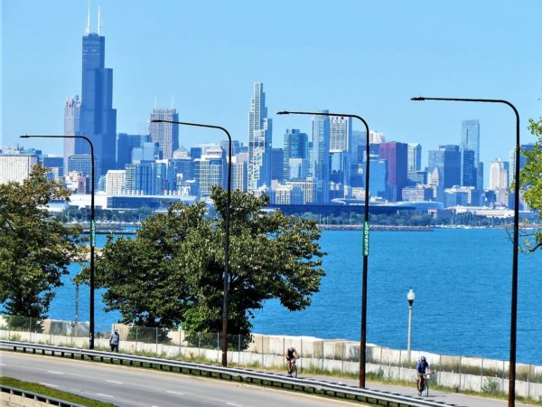 Bicycles riding on a water side paved path with the Chicago skyline in the background