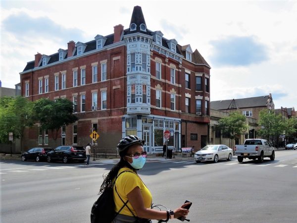 A CBA bike tour rider in front of a late 19th centurey corner three story with turret.