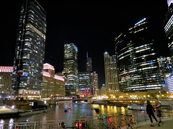 Two CBA bike tour riders looking out over a river lined with lit up skyscrapers at night