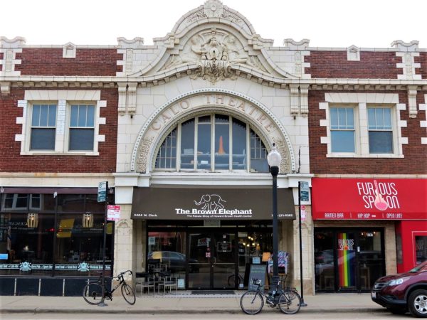 A tour bike in front of a white terra cotta arched entrance with terra cotta figures above the window.
