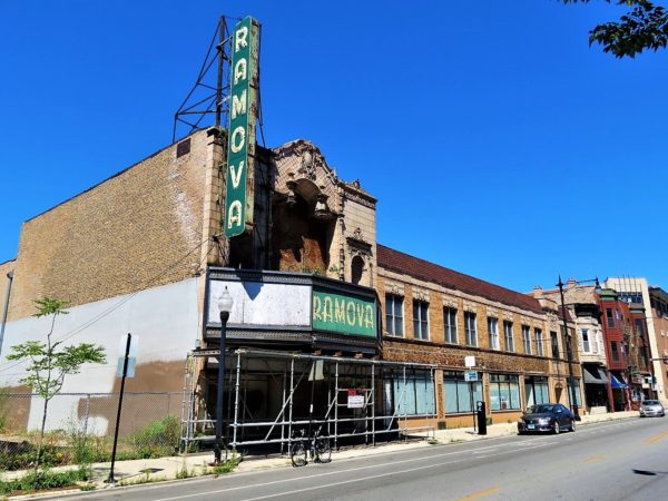 A tour bike in front of a lavish but decaying three story terra cotta theater facade with green metal vertical Ramova sign.
