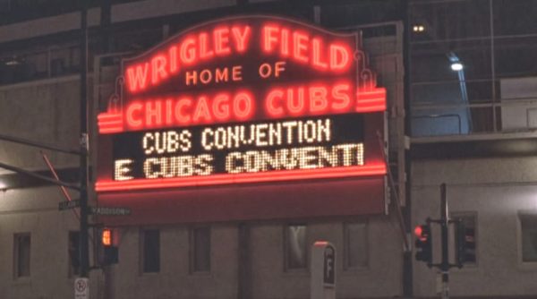 A movie still of the Wrigley Field neon board that says Cubs Convention.