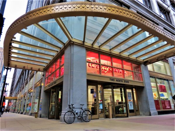 A tour bike leaning on a pillar below a gold metal rimmed see through art deco awning.