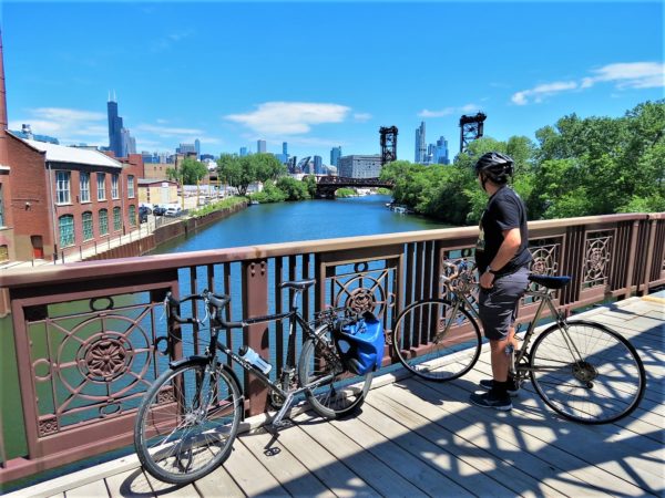 A bike tour rider looking upriver toward skyscrapers and bridges.