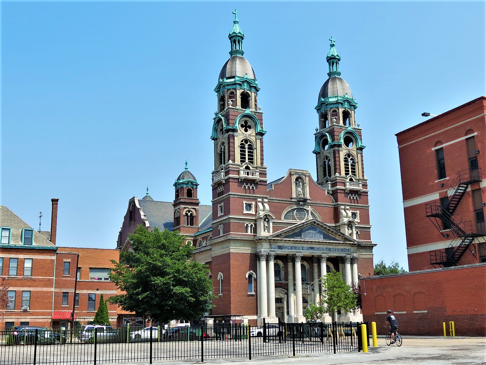 A bike tour rider looking at a baroque two towered red brick and limestone detailed church.