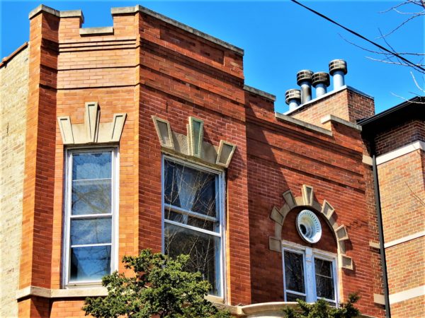 Second floor window of a red brick building with limestone "keystone" designs above.