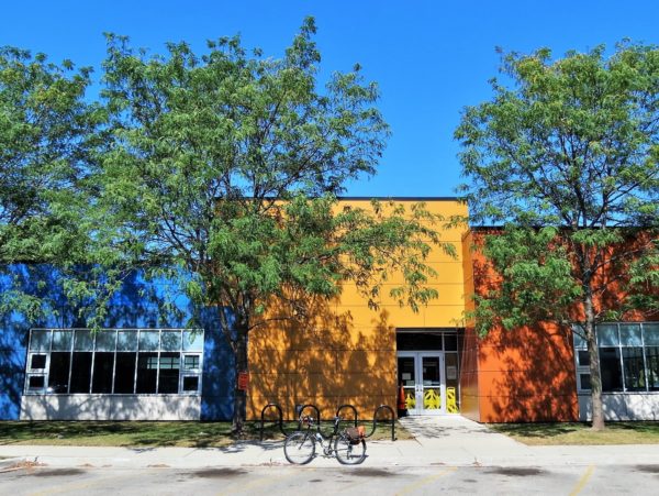 A tour bike in front of a Contemporary one story public building divided in three colors blue, yellow, burnt orange.