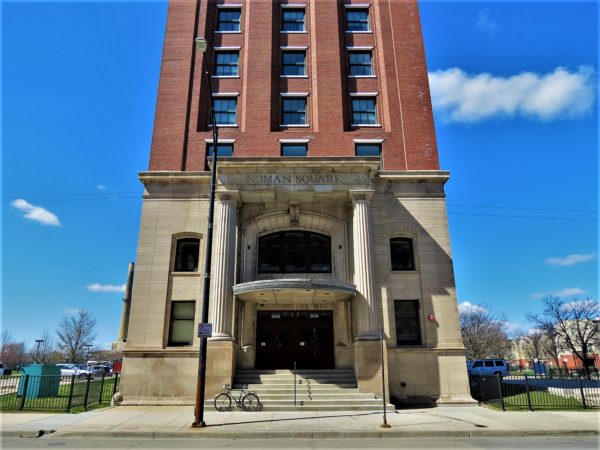 A tour bike standing in front of Neo Classic limestone entry to a red brick Prairie Stlye tower.
