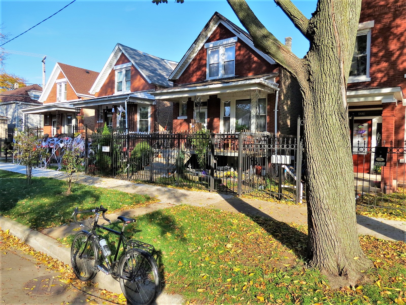 A tour bike at front of three brick one and half story workers cottages with white trim