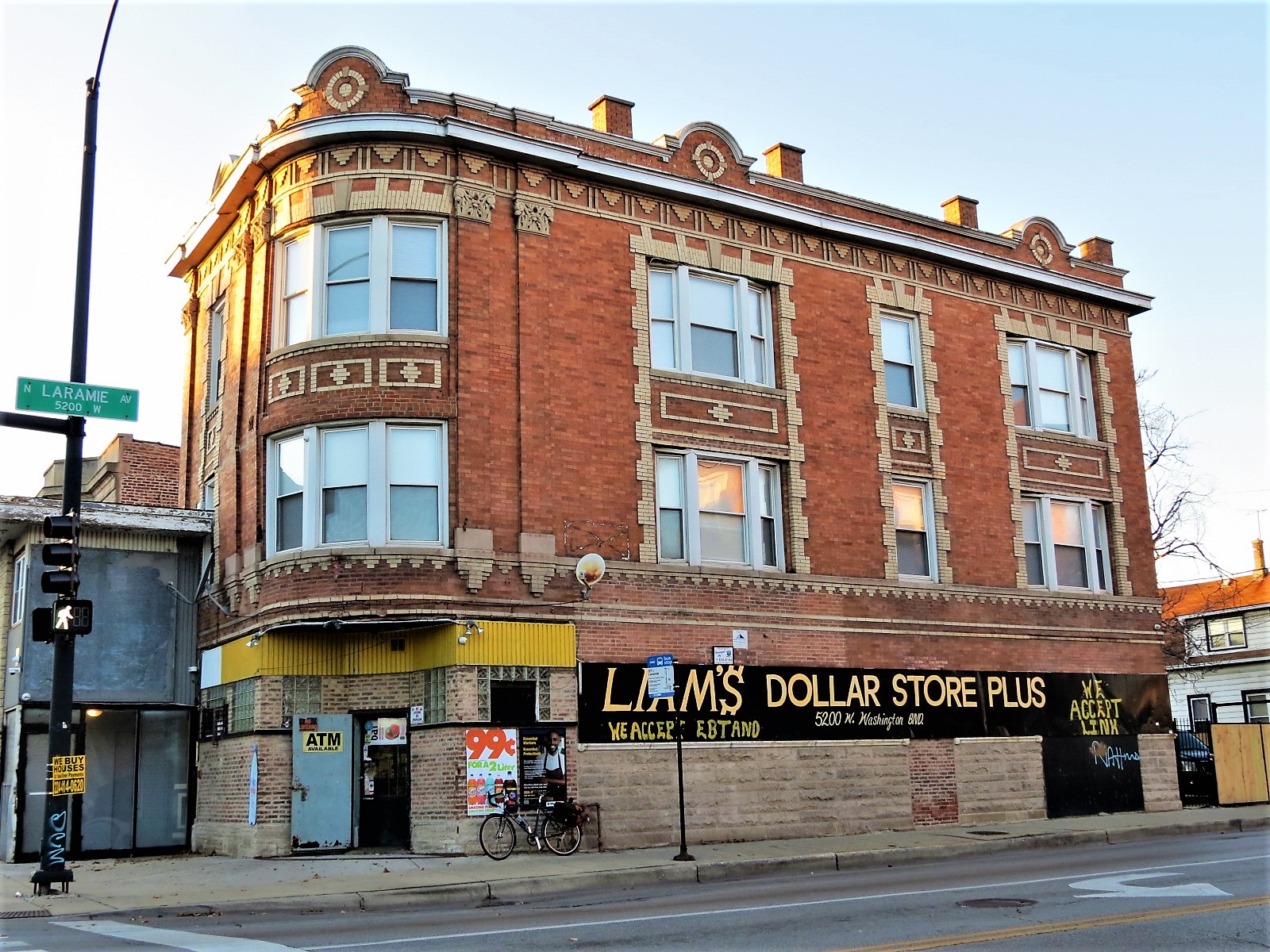 A tour bike leaning on a tan brick corner storefront with second and third floor flats decorated with cream brick designs.