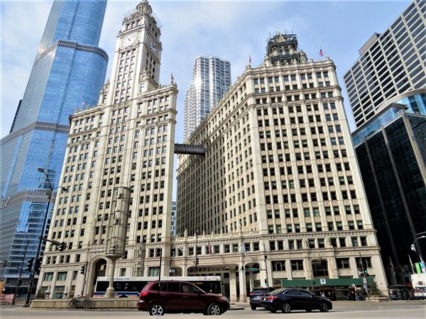 A tour bike below the Wrigley Building, two white terra cotta Art Deco skyscrapers connected by second and tenth floor walkways.